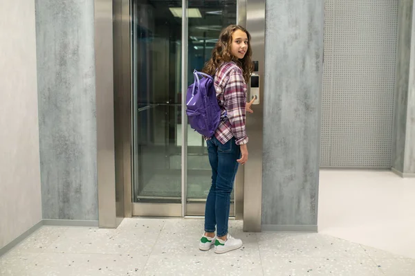 Adolescente lindo con una mochila llamando al ascensor — Foto de Stock