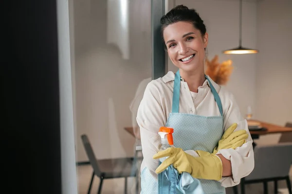 Улыбающаяся домохозяйка в фартуке, стоящая на кухне — стоковое фото