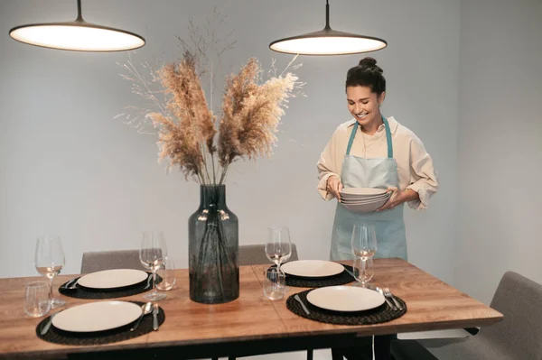 Jonge donkerharige vrouw serveert de tafel in de keuken — Stockfoto