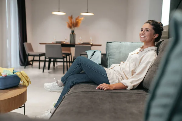 Sorrindo jovem mulher sentada em casa no sofá — Fotografia de Stock