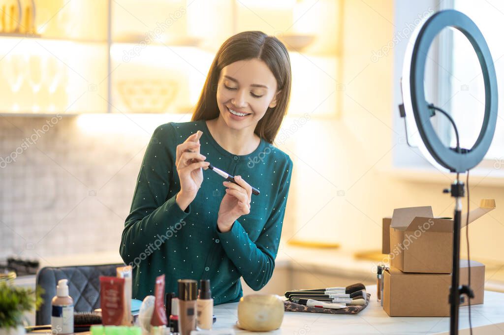 Young woman in green dress showing make up tips online