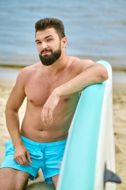 Kanolu bir adam kumsalda vakit geçiriyor.