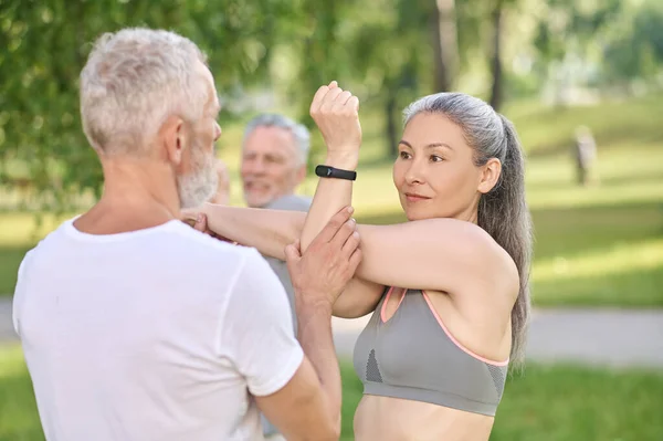 Människor som har en yogaklass i parken och sträcker på armarna — Stockfoto