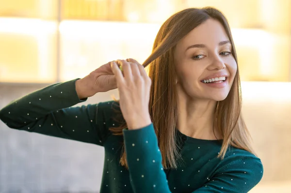 Улыбающаяся молодая женщина демонстрирует советы по уходу за волосами — стоковое фото