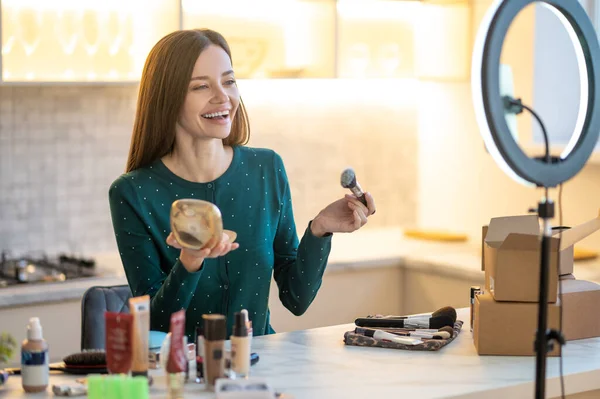 Mujer bastante joven en vestido verde que muestra consejos de maquillaje — Foto de Stock