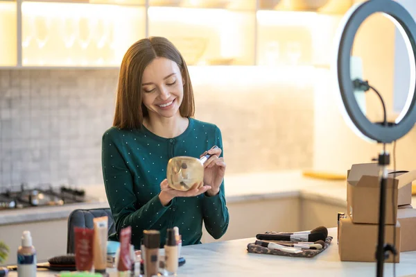 Pretty young woman in green dress showing make up tips — Stock Photo, Image