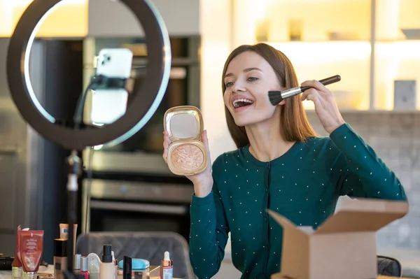 Mulher segurando escova de rosto e fazendo maquiagem — Fotografia de Stock