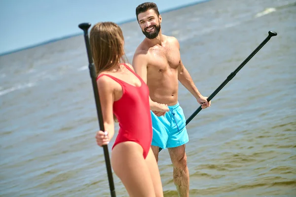 A sporty couple with oars in hands looking at each other — Stock Photo, Image