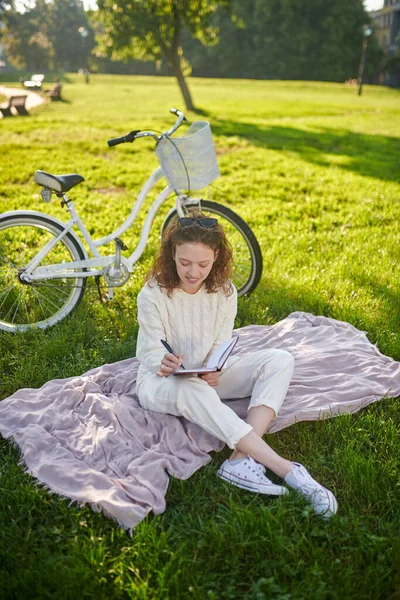 Una joven sentada en la hierba y haciendo estiramientos — Foto de Stock