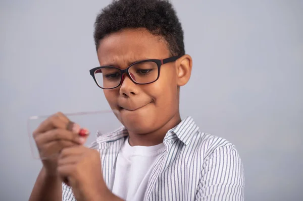 Fokuserad pojke ritar på en tunn platt glasbit — Stockfoto