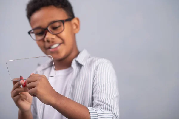Koncentrerad skolpojke som skriver på en tunn platt glasbit — Stockfoto
