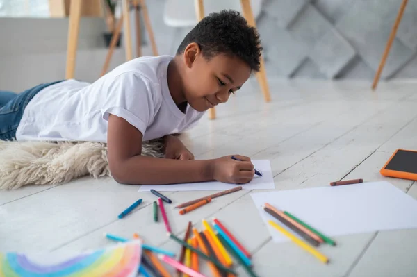 Niño dibujo con lápiz acostado en el suelo — Foto de Stock