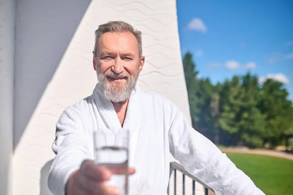 Vänlig man som erbjuder ett glas fyllt med vätska — Stockfoto