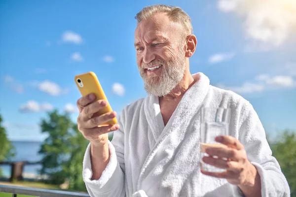 Sorrindo homem lendo uma mensagem de texto em seu smartphone — Fotografia de Stock