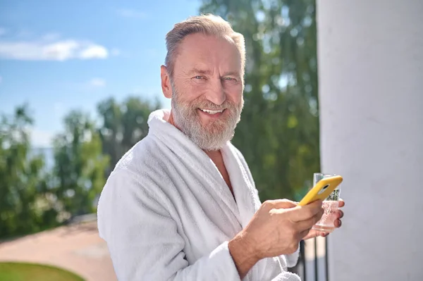 Vacaciones con una bebida y un teléfono inteligente en el balcón — Foto de Stock