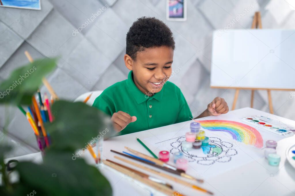 Boy sitting at table looking at pyramid of paints