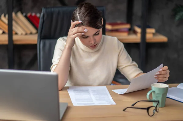 Donna d'affari concentrata che esamina un documento al tavolo di scrittura — Foto Stock