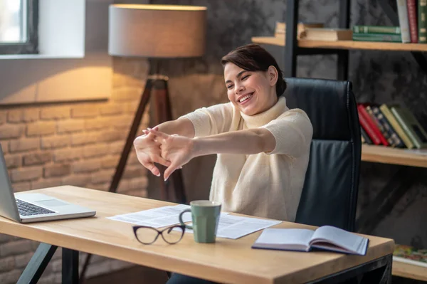 Joyous young woman cracking her knuckles at the desk — Stock Photo, Image