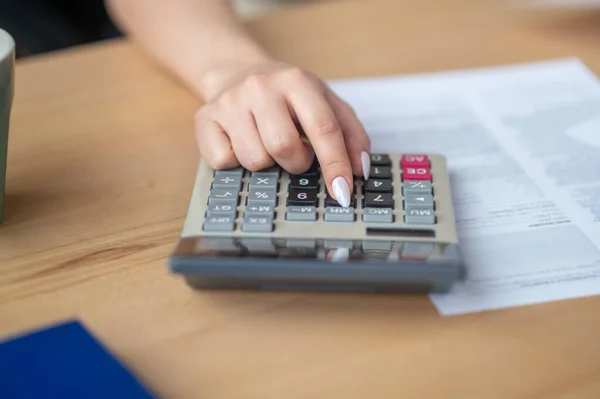 Бухгалтер, сидящий за рабочим столом с помощью карманного калькулятора — стоковое фото