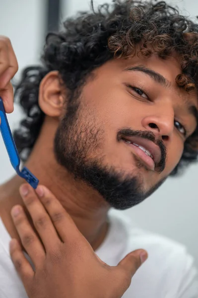 Сосредоточенный мужчина с помощью безопасной бритвы для удаления волос на шее — стоковое фото
