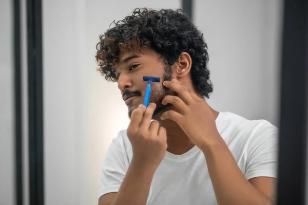 Tipo enfocado usando su afeitadora de seguridad para la depilación facial — Foto de Stock