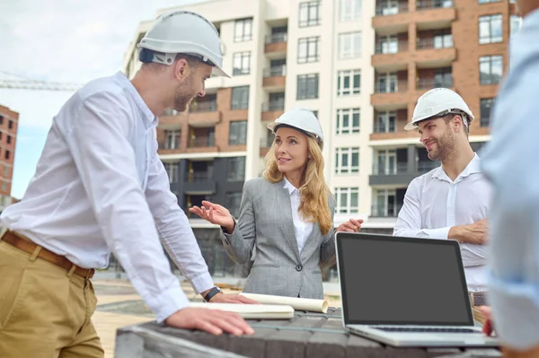 Elegante supervisore edilizio parlare con i costruttori al di fuori — Foto Stock