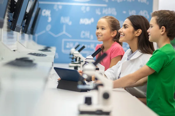 Mujer y niños de lado a la cámara mirando a la pantalla — Foto de Stock