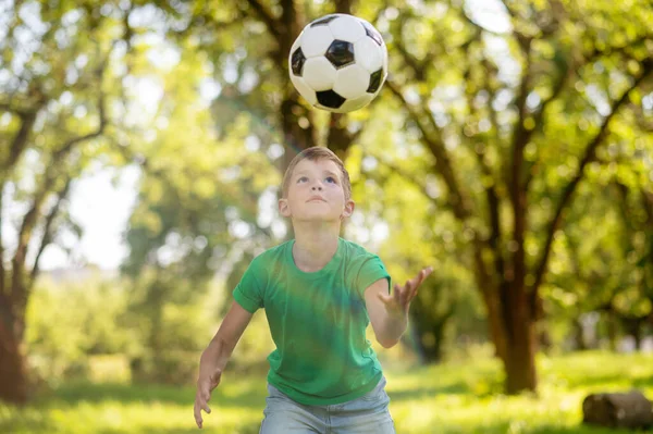 Chlapec dívá na létající fotbalový míč — Stock fotografie