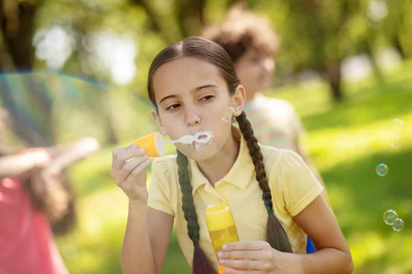 Chica haciendo burbujas de jabón en el parque — Foto de Stock