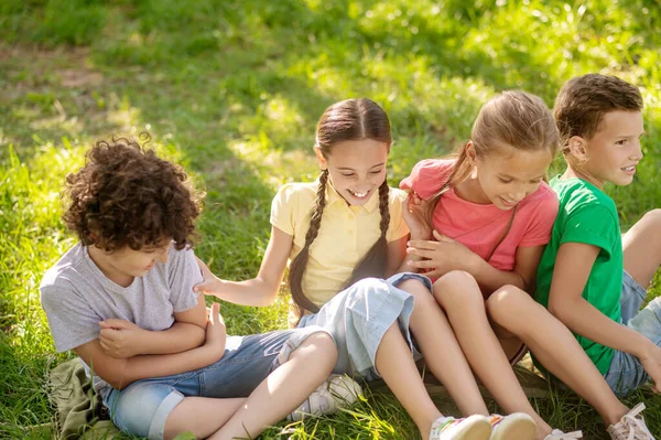 Улыбающиеся дети сидят на траве в парке — стоковое фото