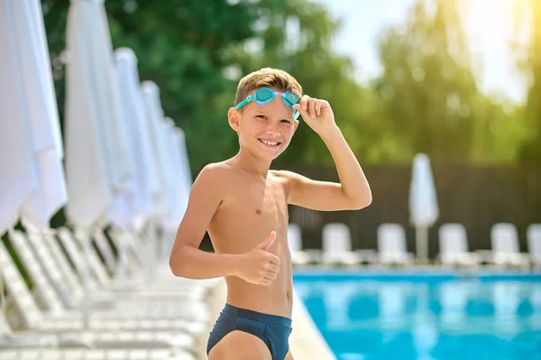 Junge lächelt mit erhobenem Zeigefinger in die Kamera — Stockfoto