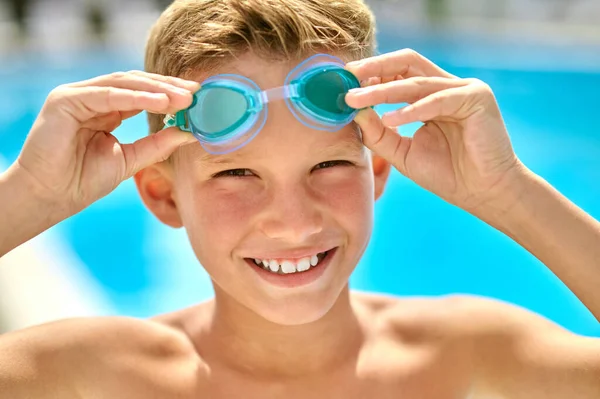 Nahaufnahme des Gesichts eines Jungen, der eine Schwimmbrille berührt — Stockfoto