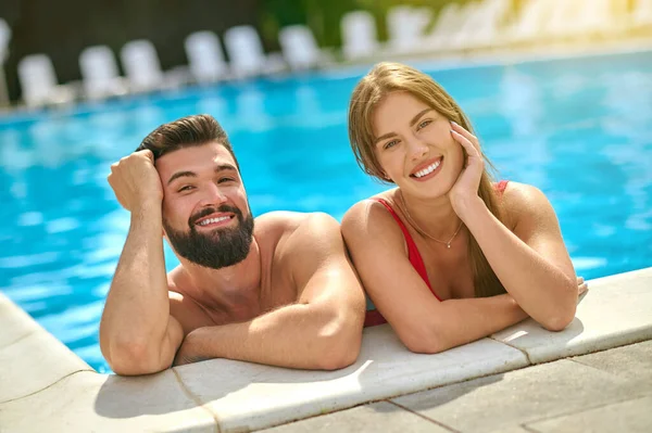 Hombre y mujer sonriendo a la cámara en la piscina — Foto de Stock