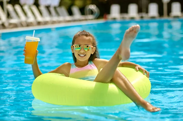 Girl on inflatable circle on water raising leg — Stock Photo, Image