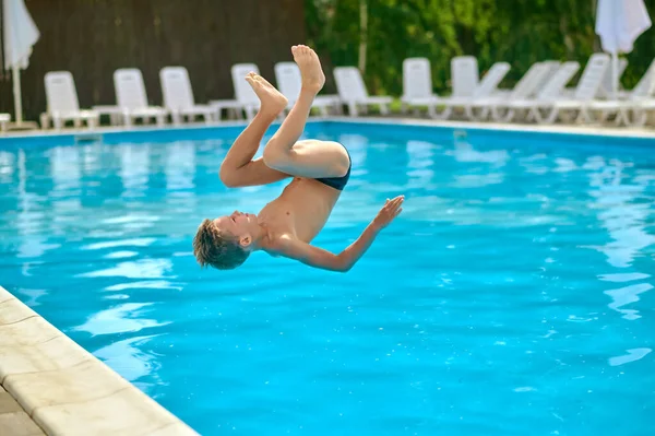 Havuzdaki çocuk havuz suyunun üstünde baş aşağı duruyor. — Stok fotoğraf