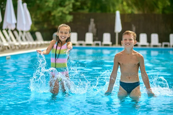 Crianças em pé na água da piscina ao ar livre — Fotografia de Stock