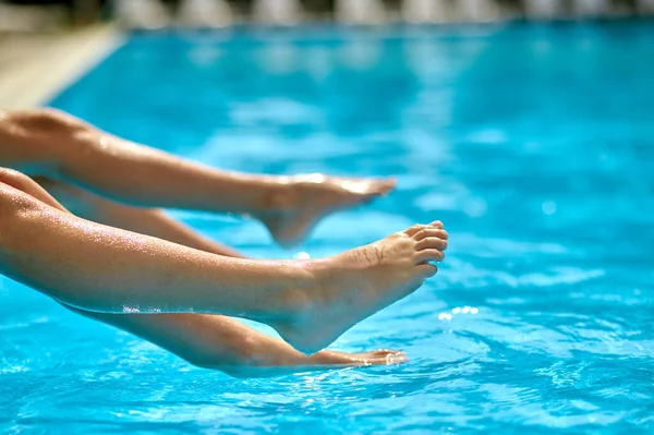 Legs of children sitting on edge of pool — Stock Photo, Image