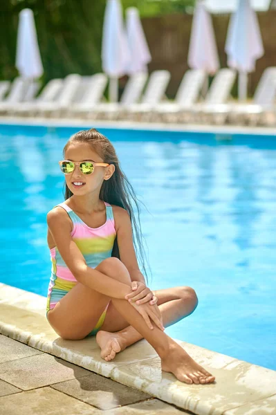 Girl sitting relaxing on edge of pool — Stock Photo, Image