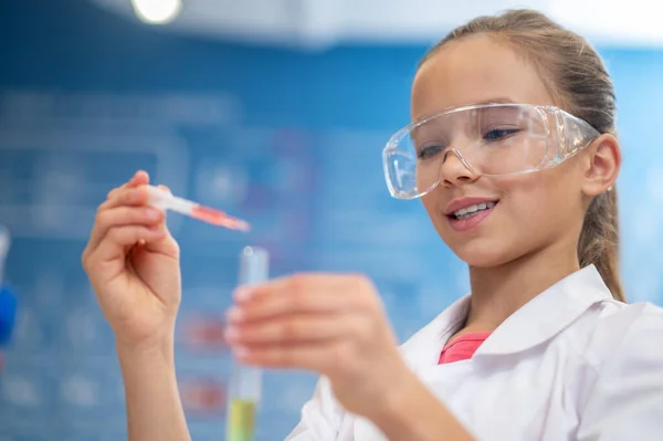 Fille ajoutant du liquide de la pipette au tube à essai — Photo