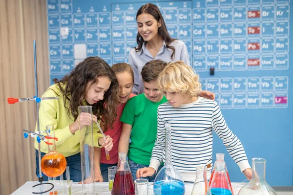 Παιδιά που κάνουν χημικά πειράματα και εκπαιδευτικοί που παρακολουθούν — Φωτογραφία Αρχείου