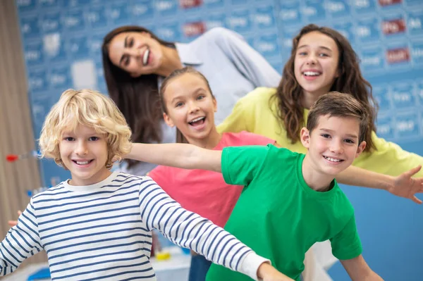 Дети и учитель в игривом настроении улыбаются в камеру — стоковое фото