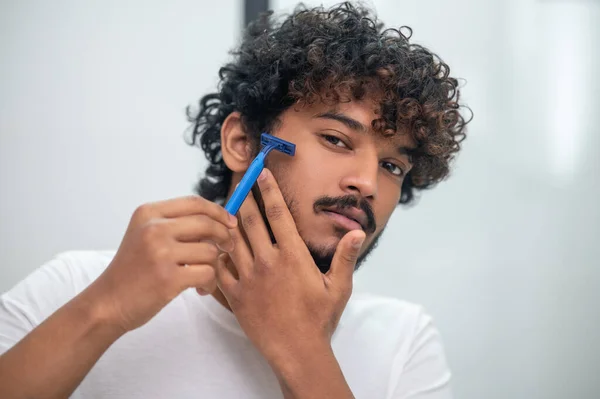 Mladý muž si holí obličej před zrcadlem — Stock fotografie