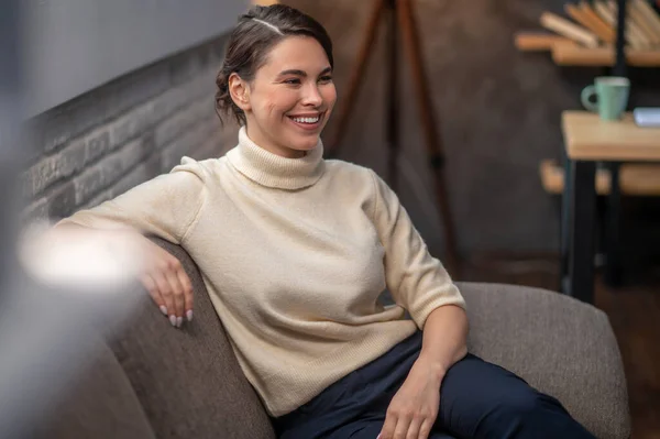 Feliz dama sentada en el sofá en el interior — Foto de Stock