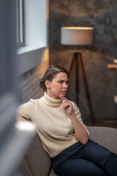 Задумчивая женщина сидит в гостиной — стоковое фото