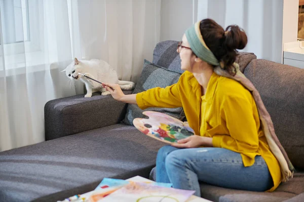 Молодая художница в студии гладит свою кошку — стоковое фото