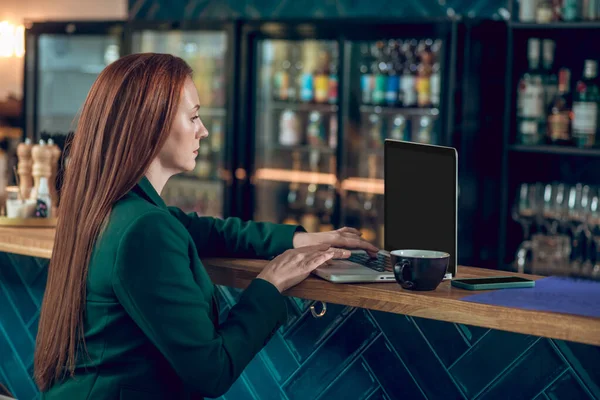 Nő nézi laptop ül a kávézóban — Stock Fotó
