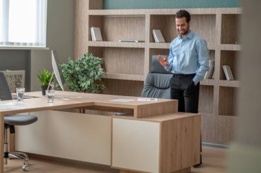 Ofiste duran ve kendinden emin görünen başarılı bir adam.