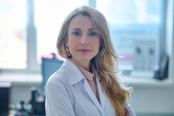 Blonde pretty doctor sitting at her place in the office — Stock Photo, Image