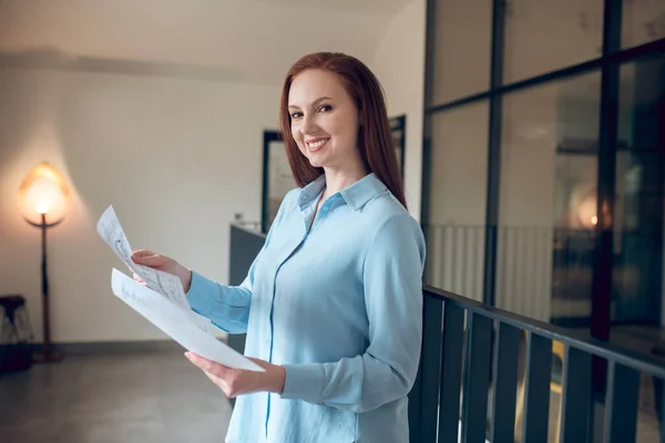 Woman with papers standing indoors looking at camera — Stock Photo, Image