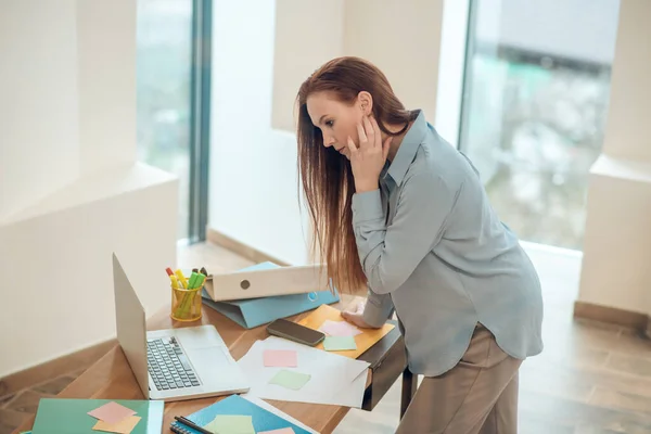 Profil för pensiv kvinna som lutar sig mot skrivbordet — Stockfoto